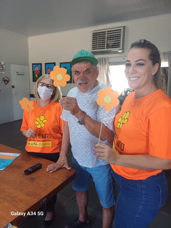 Funcionária e idoso exibindo as flores montadas
