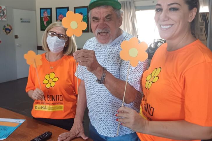 Funcionária e idoso exibindo as flores montadas